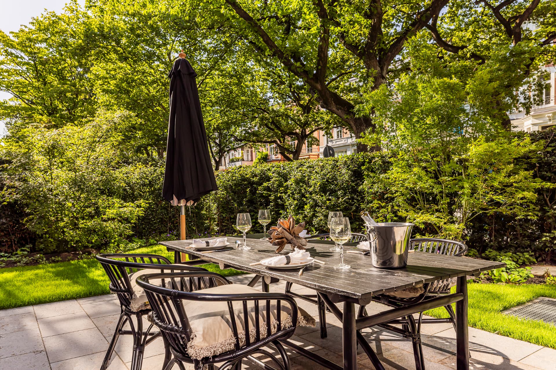 Gedeckte Tafel im Garten der Stadtvilla unter altem Baumbestand