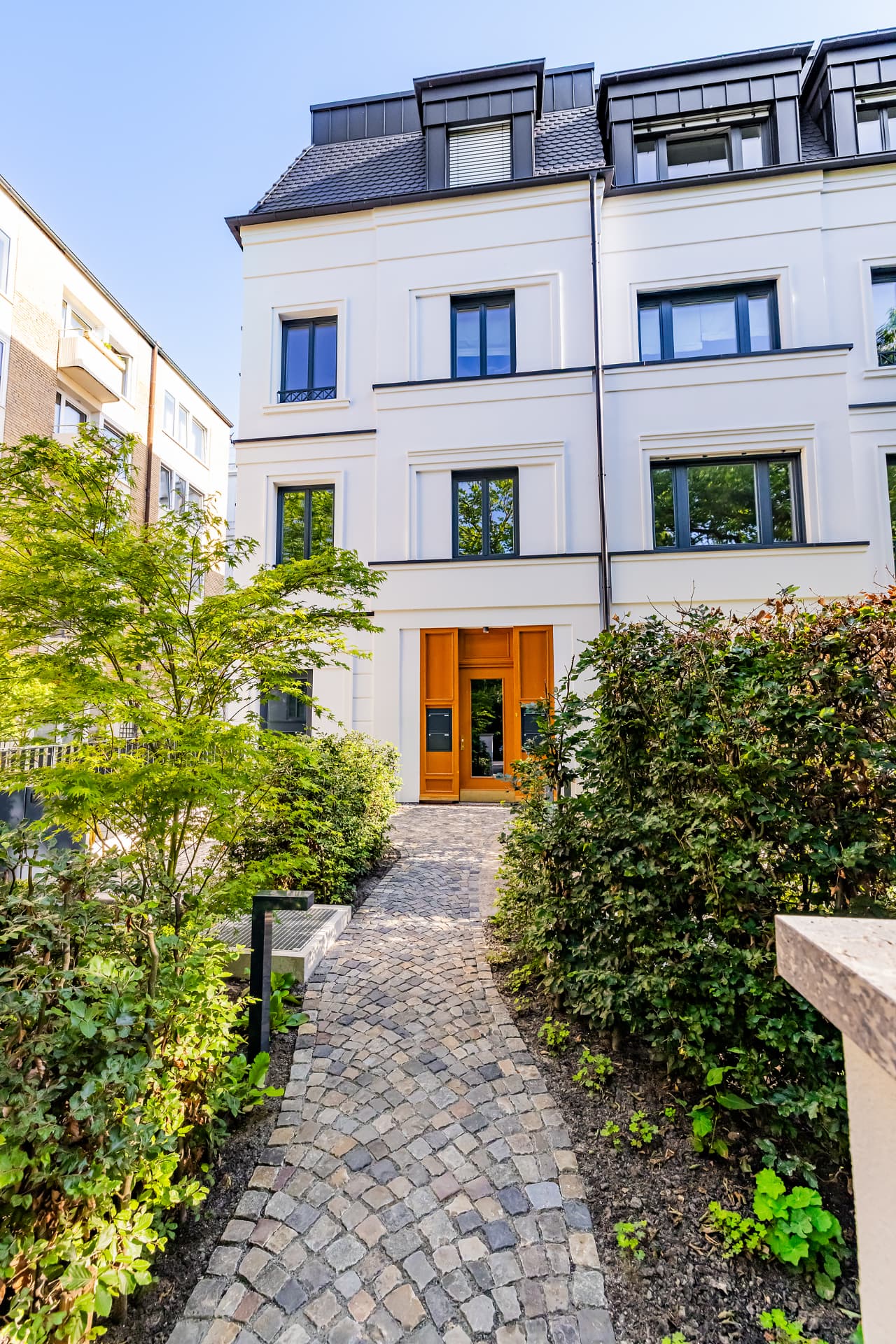 Gepflasterter Zugang durch den Vorgarten zum Hauseingang der Stadtvilla
