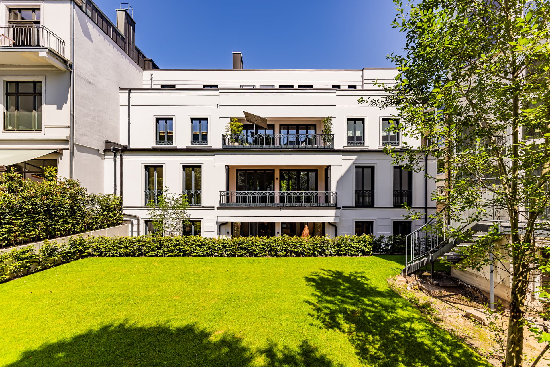 Gartenfassade der Stadtvilla mit Balkonen und Rasenfläche